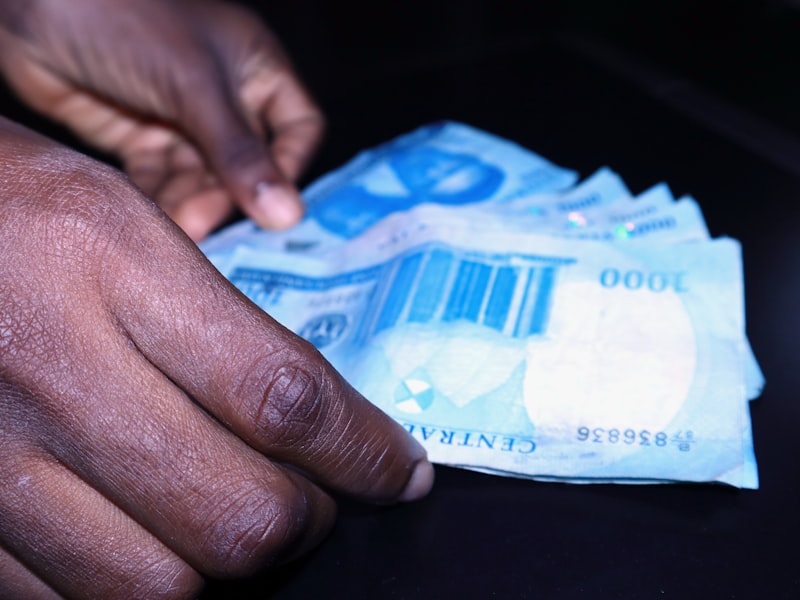 Hands counting one-thousand-naira notes at a table.
