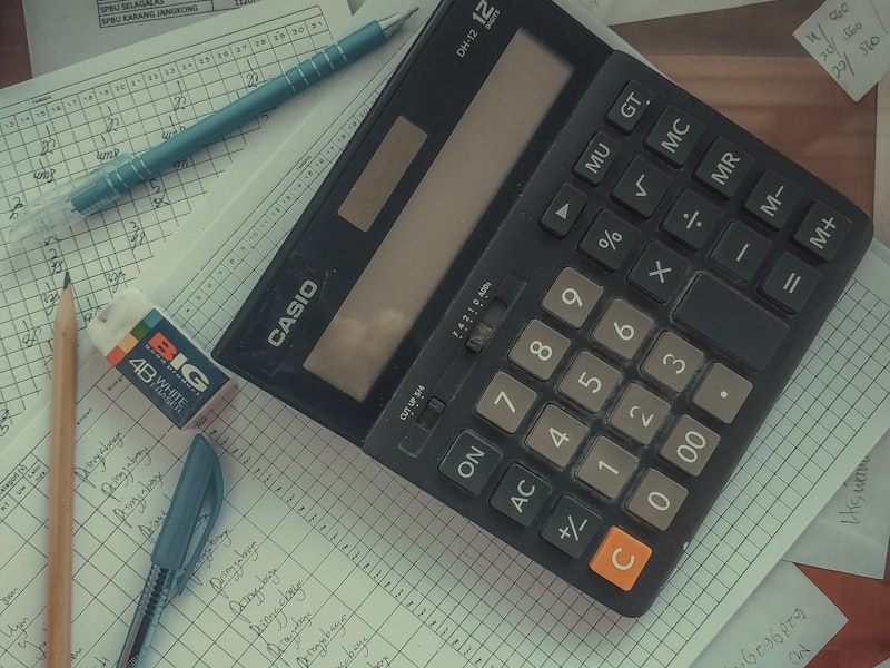 A calculator resting on a stack of handwritten ledger pages.